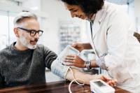Une pharmacienne mesurant la tension artérielle d’un homme âgé