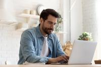 Jeune homme en train d’écrire un e-mail sur son ordinateur.