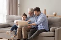 Trois générations d'hommes regardent sur ordinateur assis sur un canapé