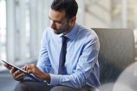 Un homme en chemise et cravate consulte sa tablette électronique