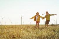 Des enfants jouent devant un parc éolien.