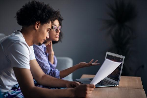 Deux personnes étudient des documents avec un ordinateur 