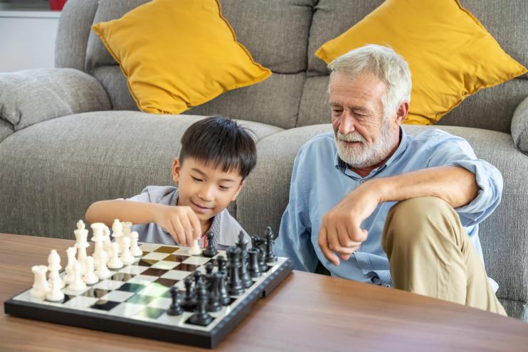 Un senior joue aux échec avec un jeune garçon