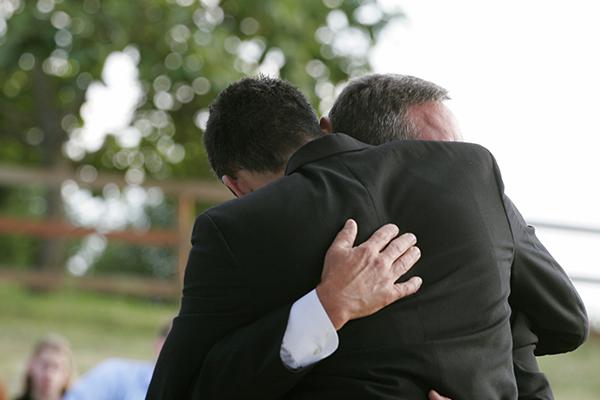 Accolade entre deux hommes durant des obsèques