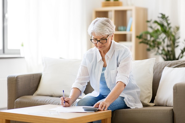 affaires, épargne, assurance rente, concept d'âge et de personnes - femme âgée avec des papiers ou des factures et une calculatrice écrivant chez elle