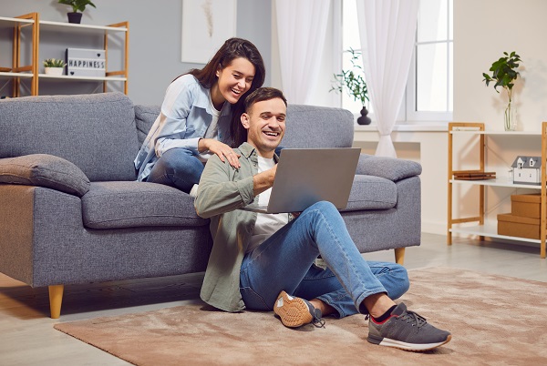 Un homme et une femme ravis chez eux avec leur ordinateur portable, gagnants d'une loterie en ligne, faisant du shopping. Un jeune couple heureux et excité se réjouit d'un e-mail positif, bénéficie d'une offre promotionnelle exceptionnelle ou d'une remise sur un ordinateur, regarde